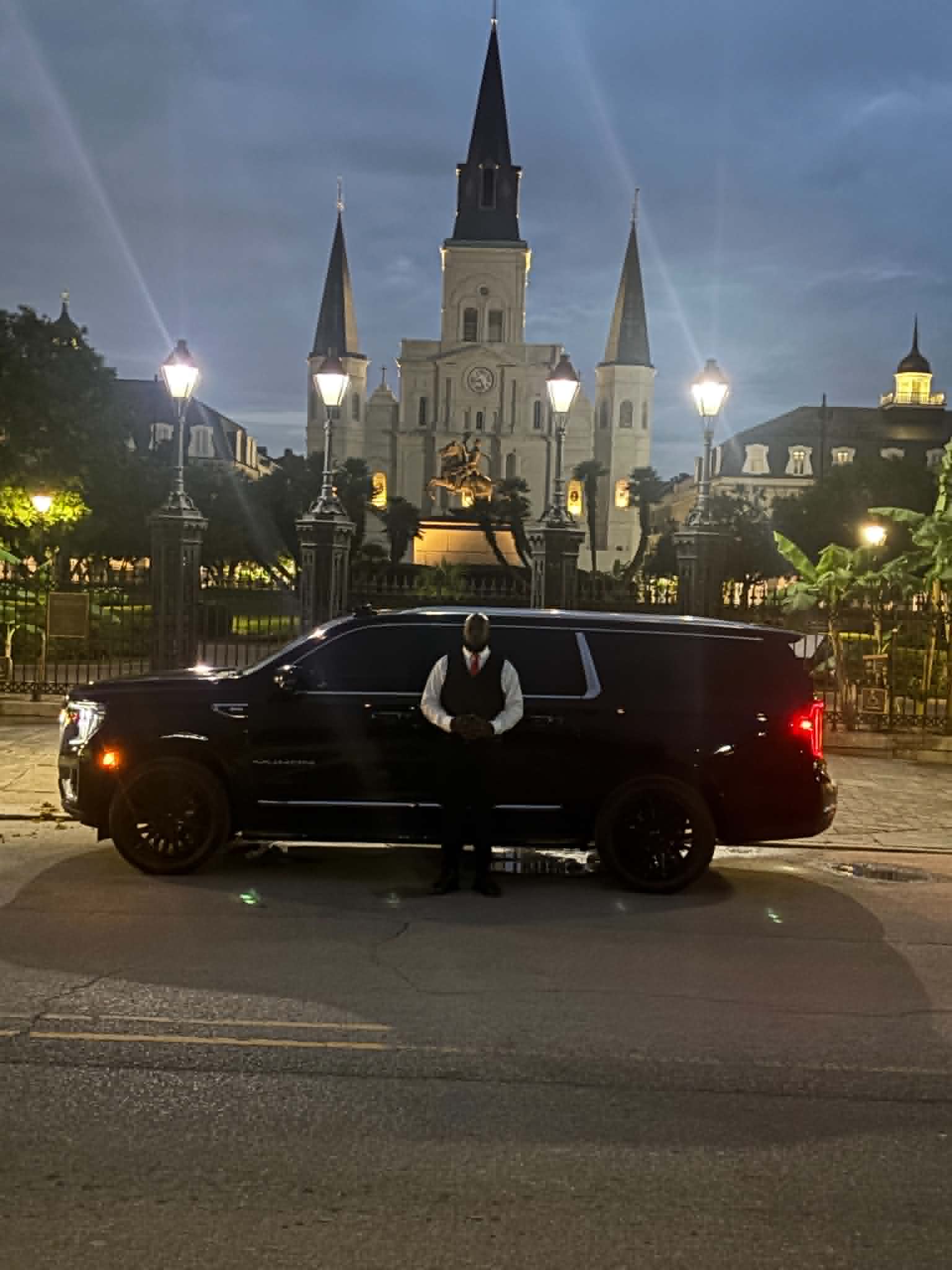 Load Up and Ride chauffeur in front of a black luxury SUV with St. Louis Cathedral in the background